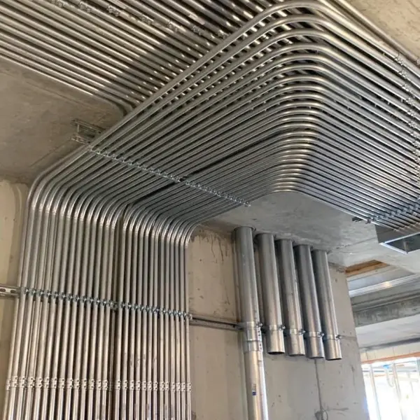 Canalizaciones EMT galvanizadas con curvas precisas en instalación eléctrica industrial — techo y bajadas organizadas según normativa RIC