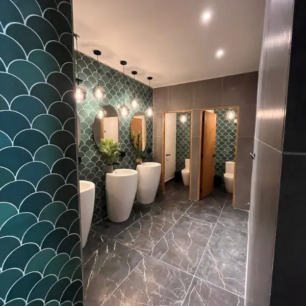 Detalle de iluminación eléctrica instalada en baño con azulejos verdes.