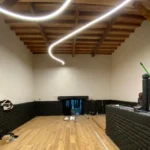 Técnicos instalando luminarias LED circulares sobre andamio para proyecto eléctrico en Las Condes.