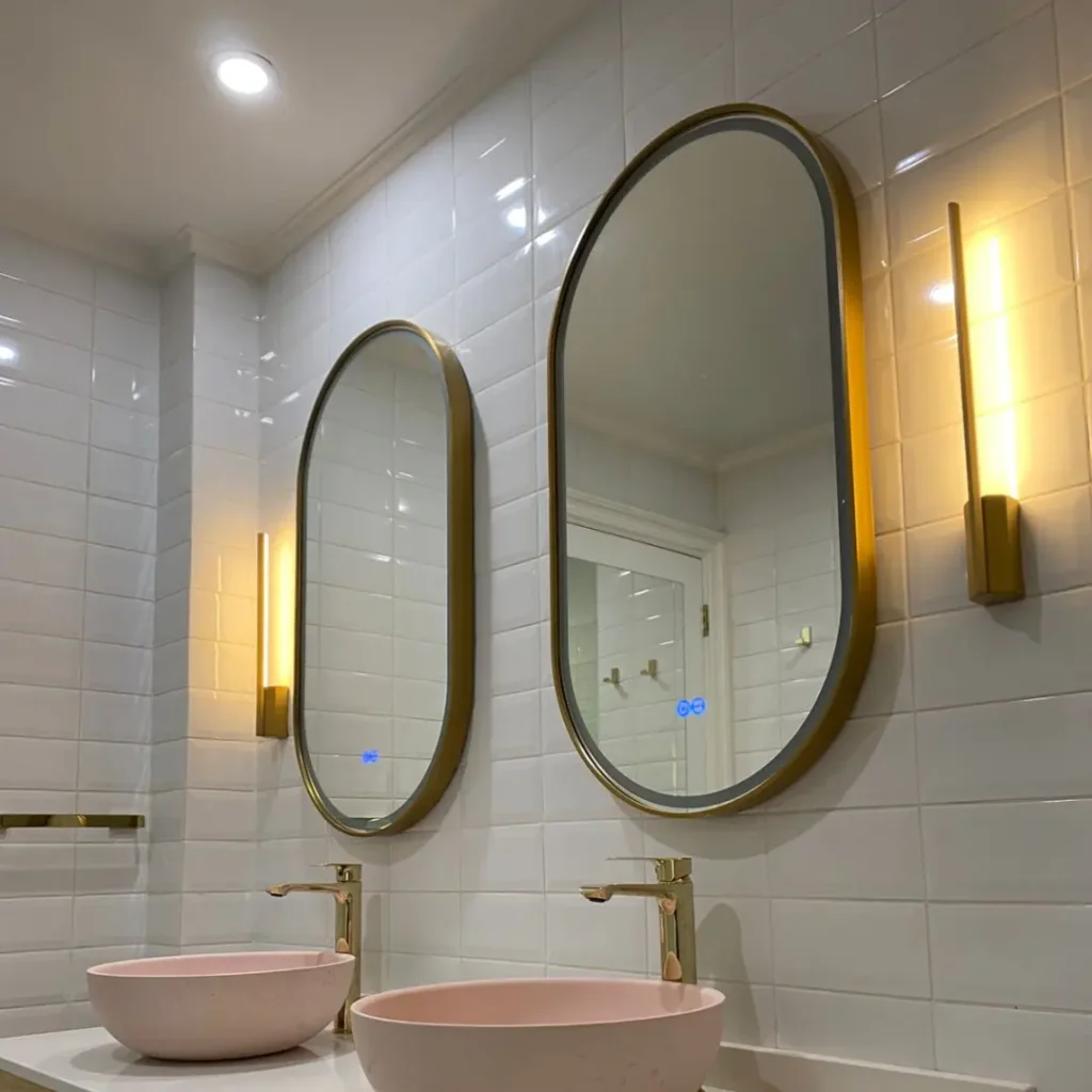 Iluminación de baño con espejos retroiluminados y apliques murales instalada en vivienda residencial de Lo Barnechea